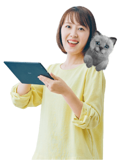 写真：猫を肩に乗せ、ノートパソコンを開き笑顔でこちらを見る女性