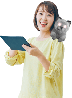 写真：猫を肩に乗せ、ノートパソコンを開き笑顔でこちらを見る女性